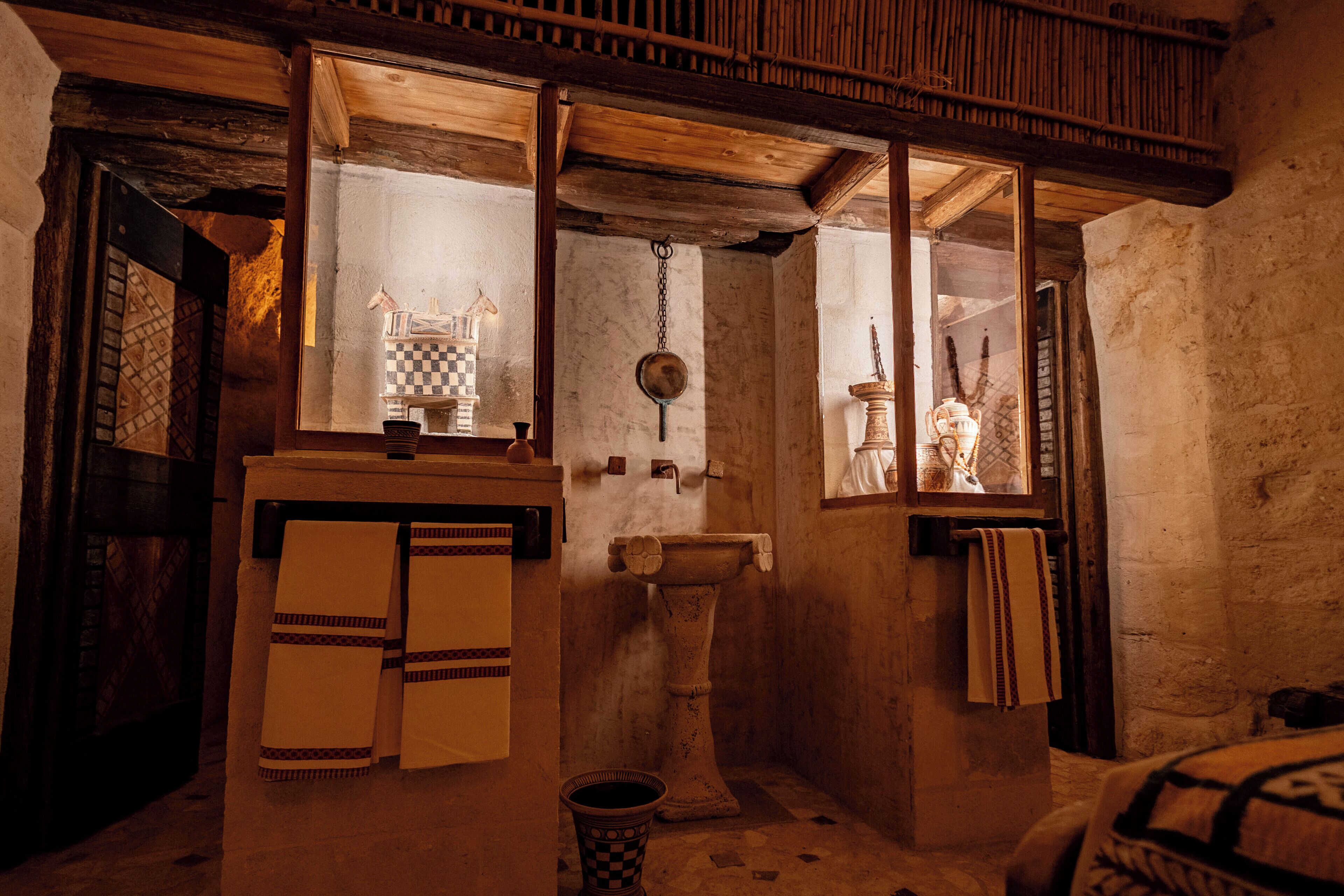 A rustic room with a wooden ceiling, a checkered towel, a basin, and a window with a view.
