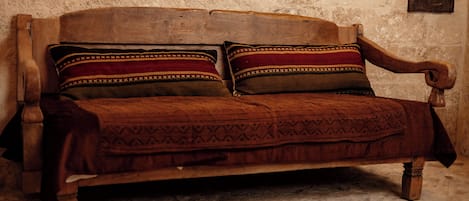 A wooden sofa with patterned cushions against a textured wall.