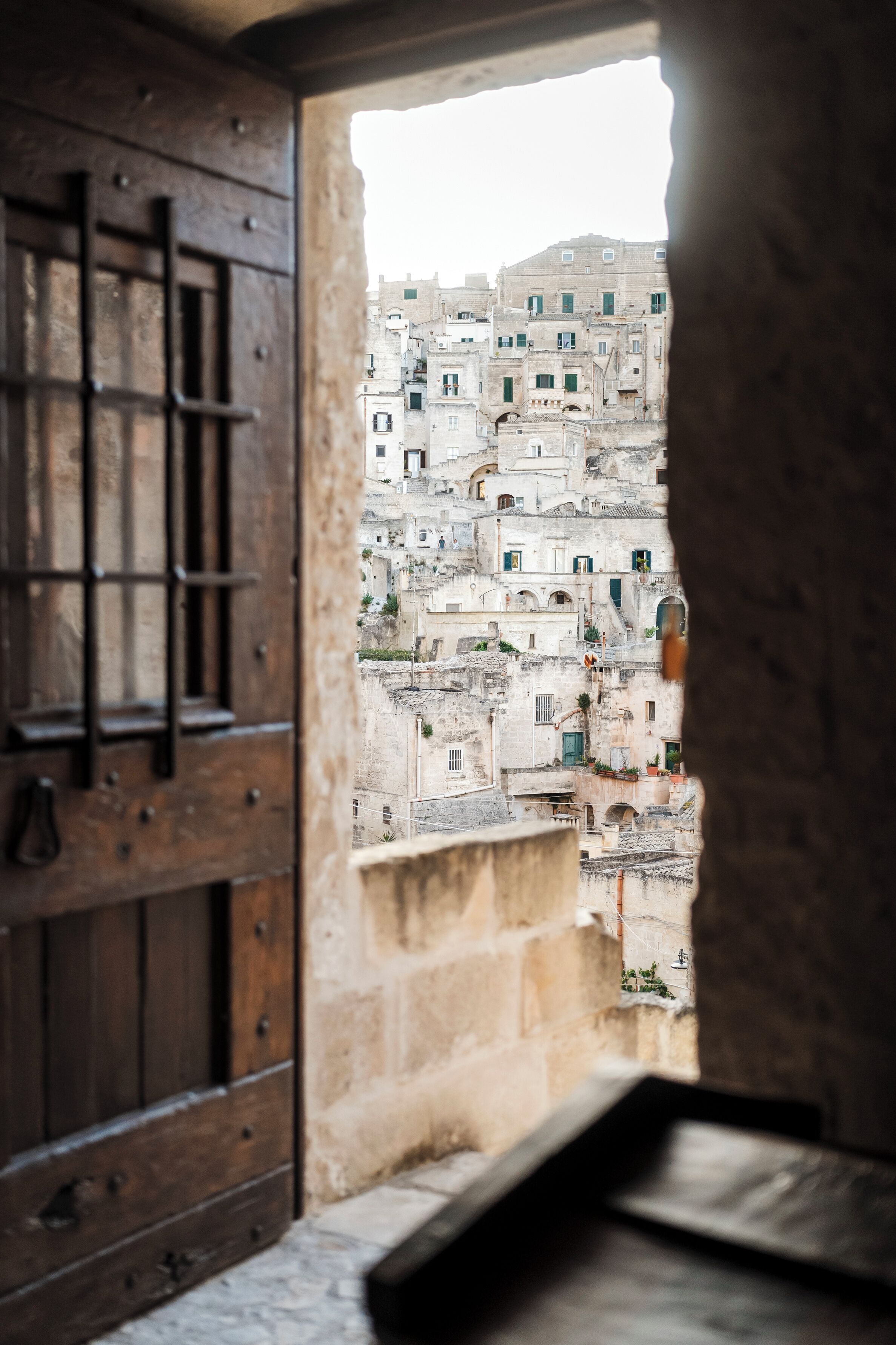 Vista a través de una puerta de madera de un edificio histórico con múltiples balcones y ventanas, lo que sugiere un estilo arquitectónico tradicional.