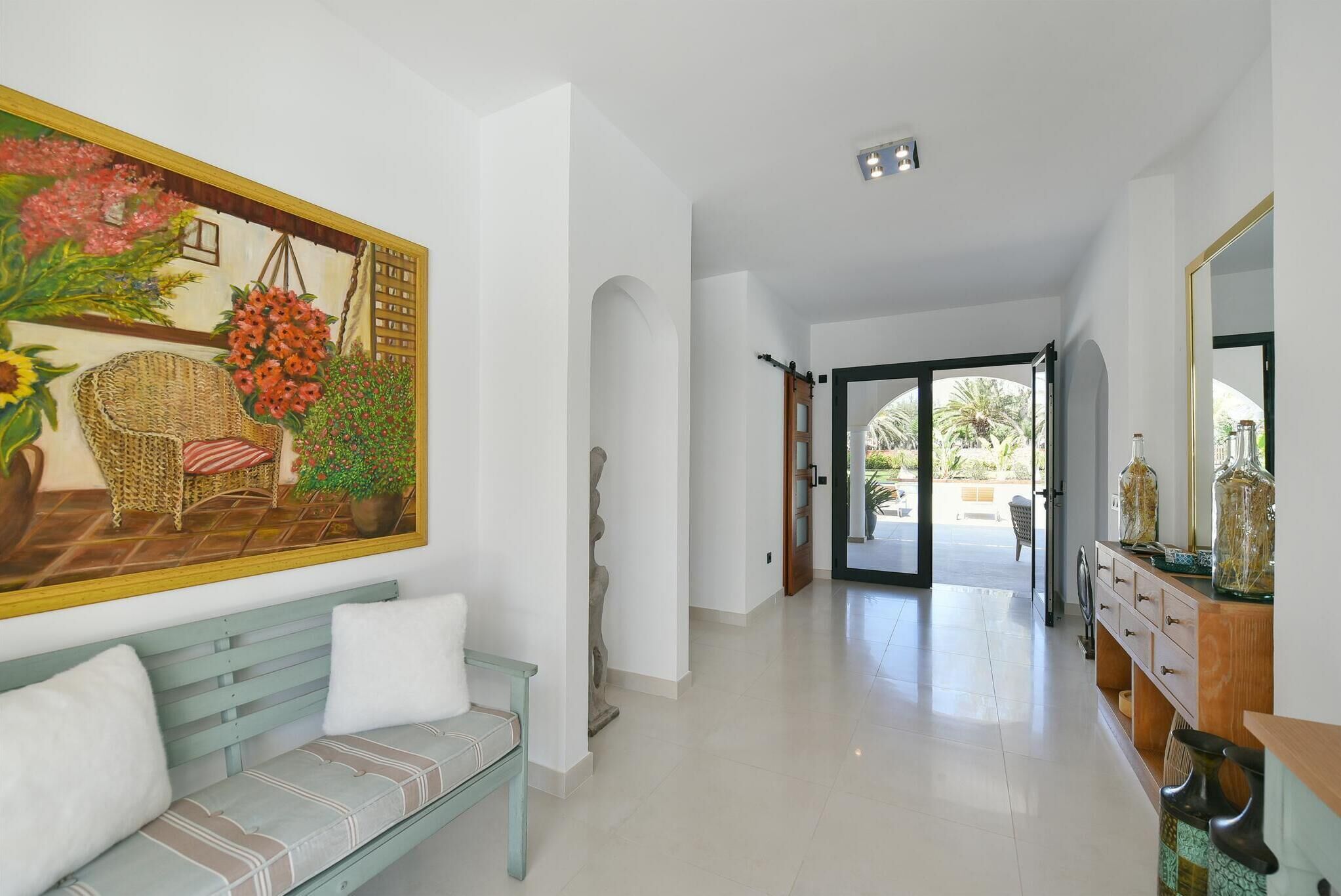 A spacious hallway with a bench, a large painting, and a wooden cabinet with decorative items.