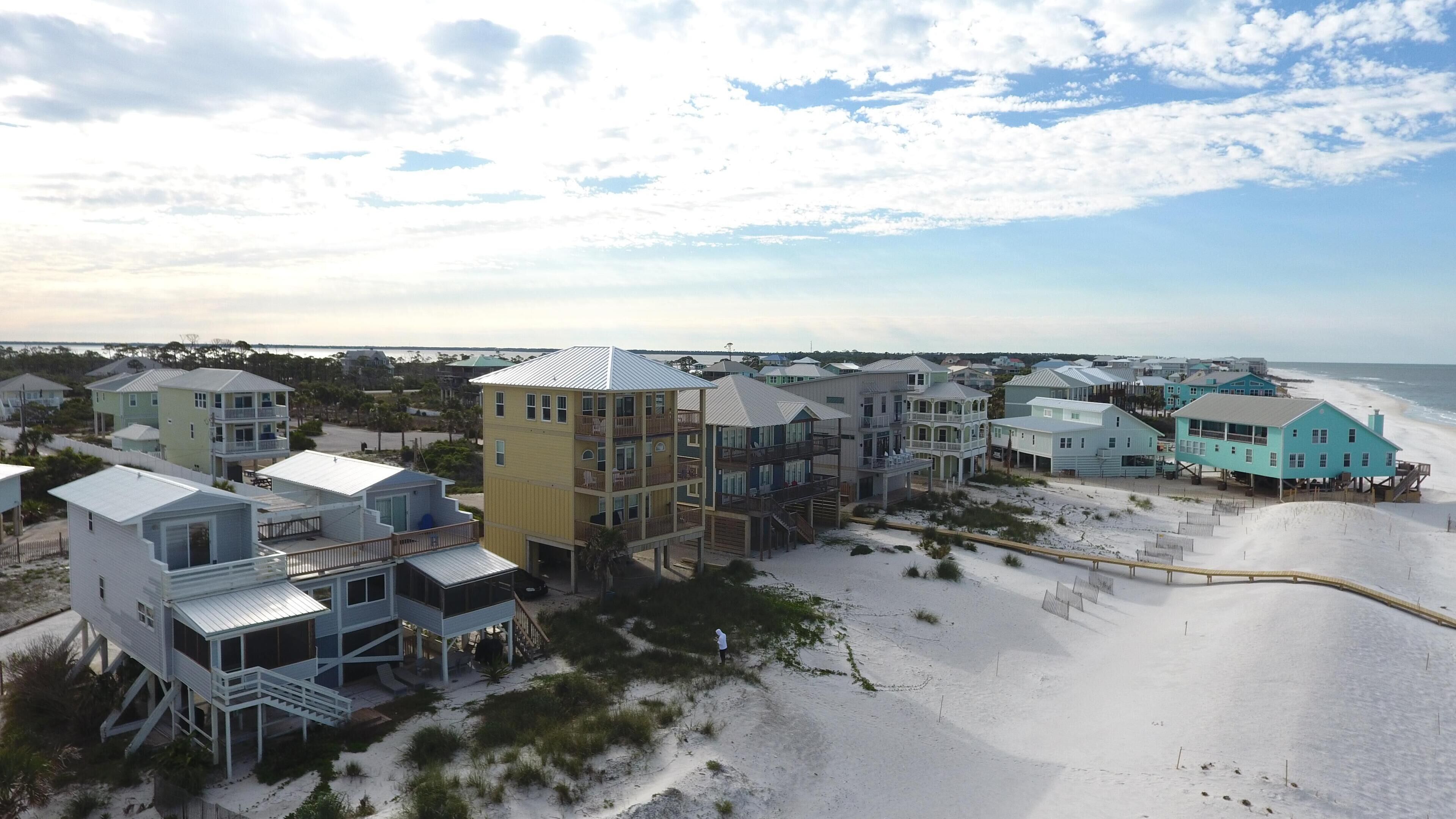 Una zona residencial costera con propiedades frente al mar, incluyendo edificios de varios pisos con balcones y acceso directo a la playa.