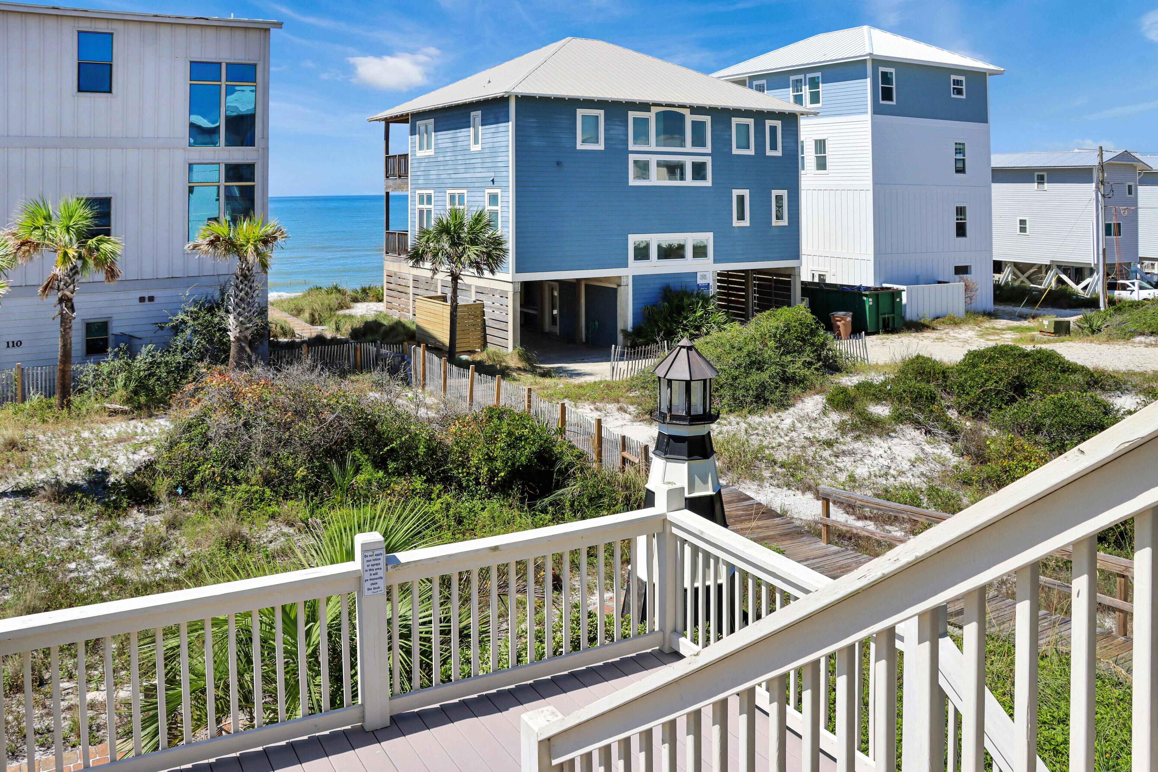 A beachfront property with a white deck, a lighthouse, and a view of the ocean.