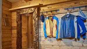 A wooden cabin interior with a bench, a coat rack with jackets, and a door with a rustic frame. - Apartment in Leutasch Near Ski Trails (Leutasch)