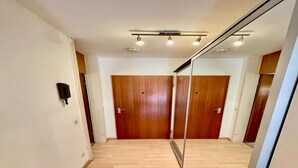 Een gang met houten deuren, een plafondlamp en een intercom op de muur.
