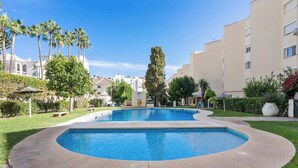 Ein Pool mit geschwungener Kante, umgeben von einer Rasenfläche und Palmen.
