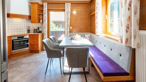 Una cocina compacta con armarios de madera, horno empotrado y zona de comedor con banco y sillas.