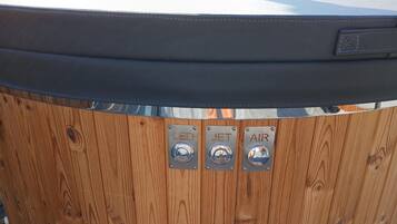 Una vasca idromassaggio in legno con tre pulsanti di controllo etichettati “LED”, “JET” e “AIR”.