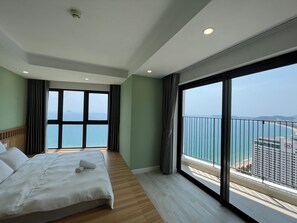 A hotel room with a large bed, a view of the sea, and a balcony with a railing. - Apartment PHONGLIEM 1 (Nha Trang)