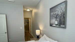 A bedroom with a bed, a nightstand, a lamp, and a painting on the wall.