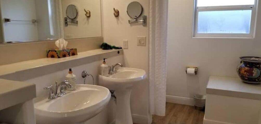 A bathroom with two sinks, a mirror, and a window.