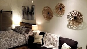 Une chambre à coucher comprenant un lit, des tables de chevet, des lampes et des œuvres d’art décoratives accrochées au mur.
