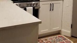Une cuisine avec des armoires blanches, un four à micro-ondes en acier inoxydable, une cuisinière et un évier.
