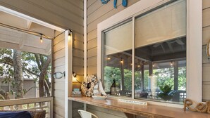 A covered outdoor seating area with wicker furniture and a wooden table. - Great Cottage at Hidden Dunes with Free Seasonal Beach Chair Setup! (Miramar Beach)