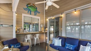 A cozy covered porch with wicker furniture, a ceiling fan, and string lights. - Great Cottage at Hidden Dunes with Free Seasonal Beach Chair Setup! (Miramar Beach)