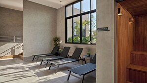 A spa area with sun loungers, a staircase, and a wooden sauna door. - Movinn Expand - Pinheiros (São Paulo)