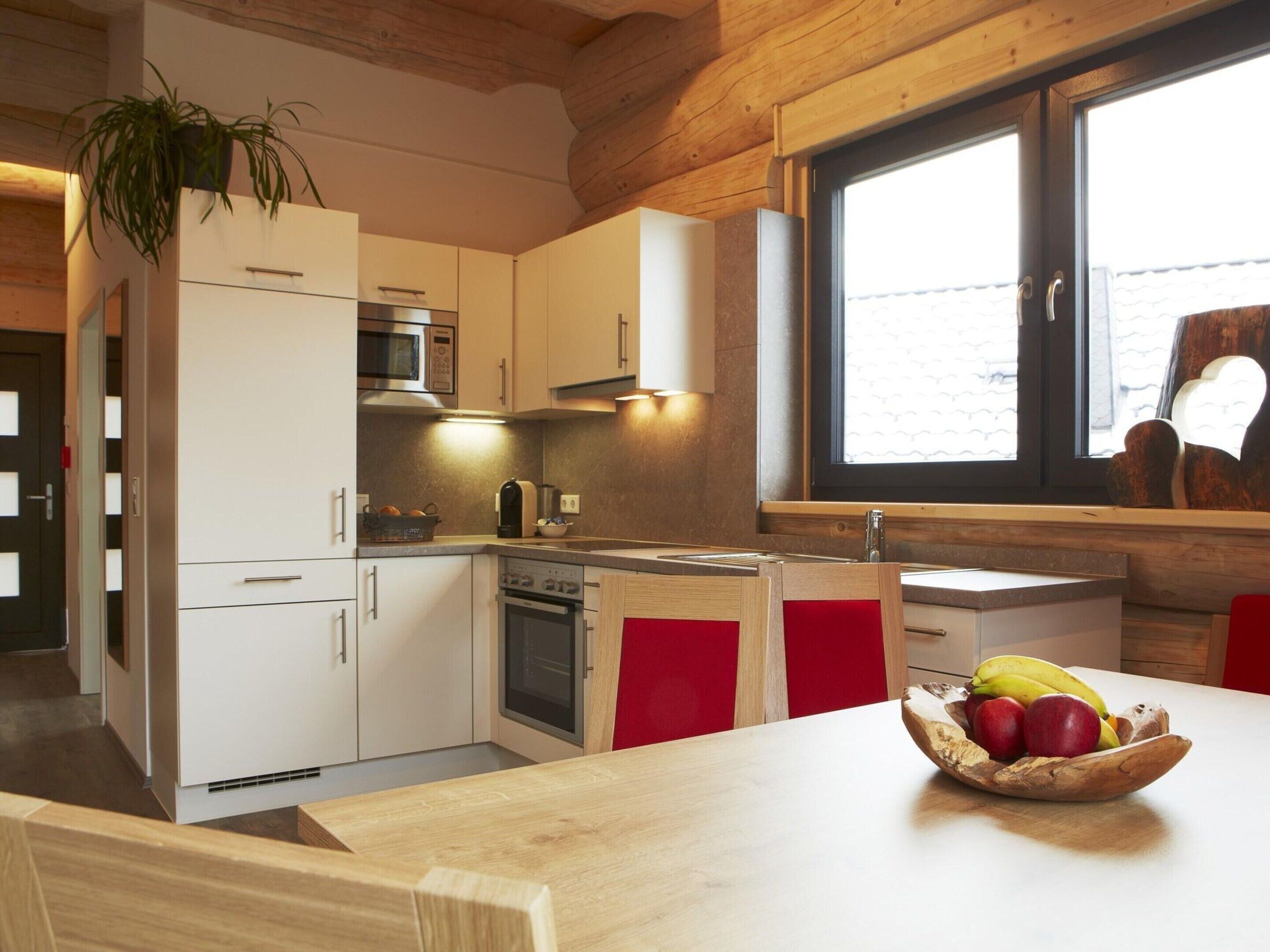 A modern kitchen with white cabinets, a microwave, stove, and a window with a view of the outside.