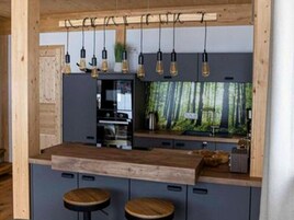 Una cocina moderna con encimera de madera, luces colgantes y horno integrado.