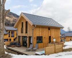 Una cabaña de madera con terraza, jacuzzi y vistas a las montañas.