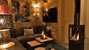 A cozy living room with a stone wall, a fireplace, a sofa, and a television. - Attractive Chalet With Sauna (Sankt Georgen am Kreischberg)