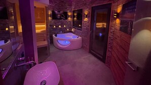 A modern bathroom with a stone wall, a large bathtub, and a mirror. - Attractive Chalet With Sauna (Sankt Georgen am Kreischberg)