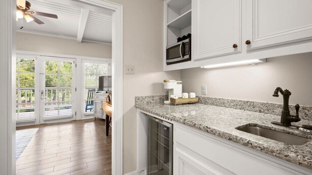 Una cocina con muebles blancos, encimera de granito y pileta de acero inoxidable.