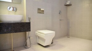 Une salle de bain moderne avec un lavabo, des toilettes et une douche, le tout de couleur blanche.