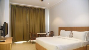 Une chambre d’hôtel avec un lit, un bureau, une chaise et un téléviseur.