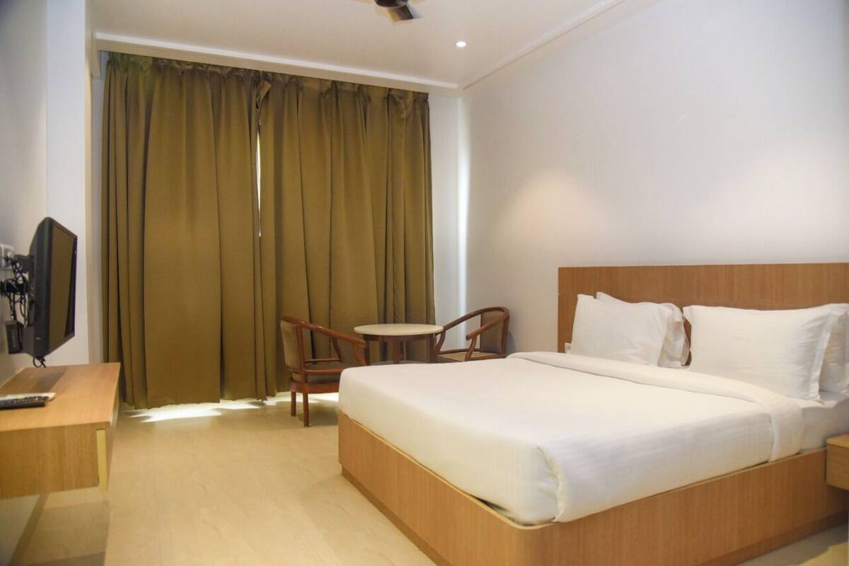 A hotel room with a bed, a desk, a chair, and a television.