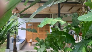 Une maison moderne dotée d’une terrasse en bois, d’un espace salon et d’une végétation luxuriante.
