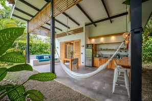 A modern kitchen with a dining area, a hammock, and a view of the outdoors.