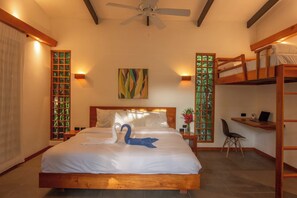 Ein Hotelzimmer mit Bett, Schreibtisch, Stuhl, Deckenventilator und Fenster mit Blick.