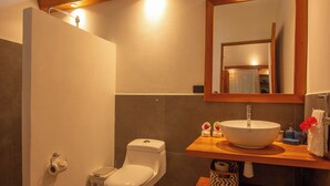 Un baño con inodoro, lavamanos, espejo y toallero.