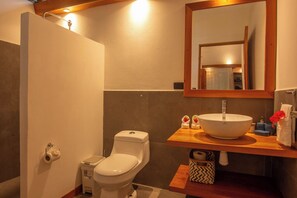 Une salle de bain équipée de toilettes, d’un lavabo, d’un miroir et d’un porte-serviettes.