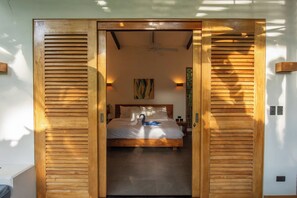 Une chambre à coucher avec un lit, un ventilateur de plafond et une œuvre d’art accrochée au mur.