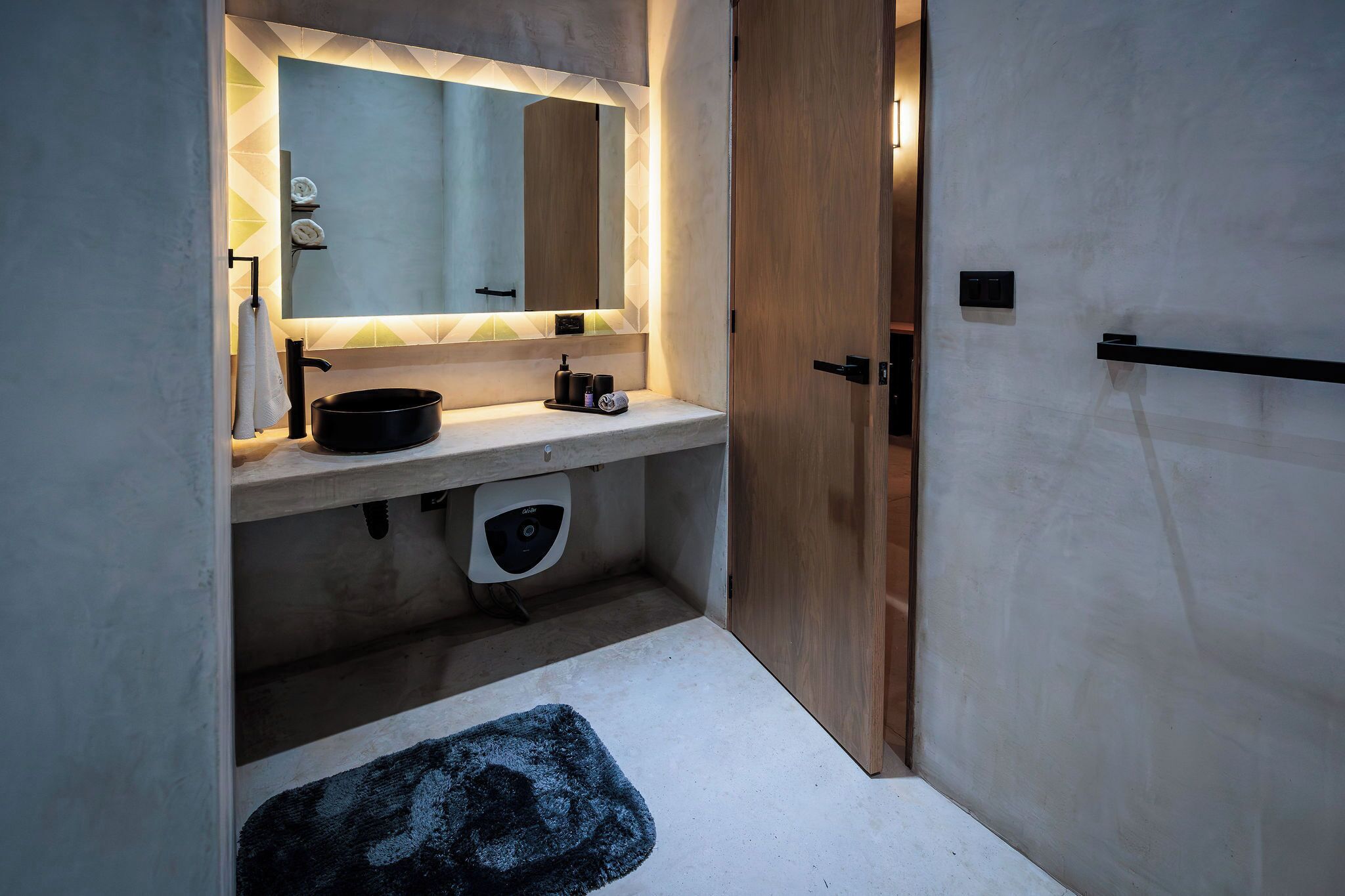 Ein modernes Badezimmer mit einem großen Spiegel, einem Waschbecken und einer Toilette.