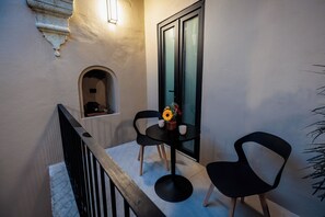 A balcony with a small table, two chairs, a vase with flowers, and a door with frosted glass. - Casa 1800 Oaxaca Boutique Hotel (Oaxaca)