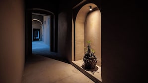 Un couloir faiblement éclairé, avec une plante en pot et une porte au fond.