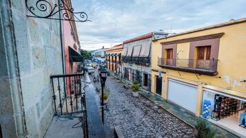 A cobblestone street with buildings on either side, featuring balconies and storefronts.