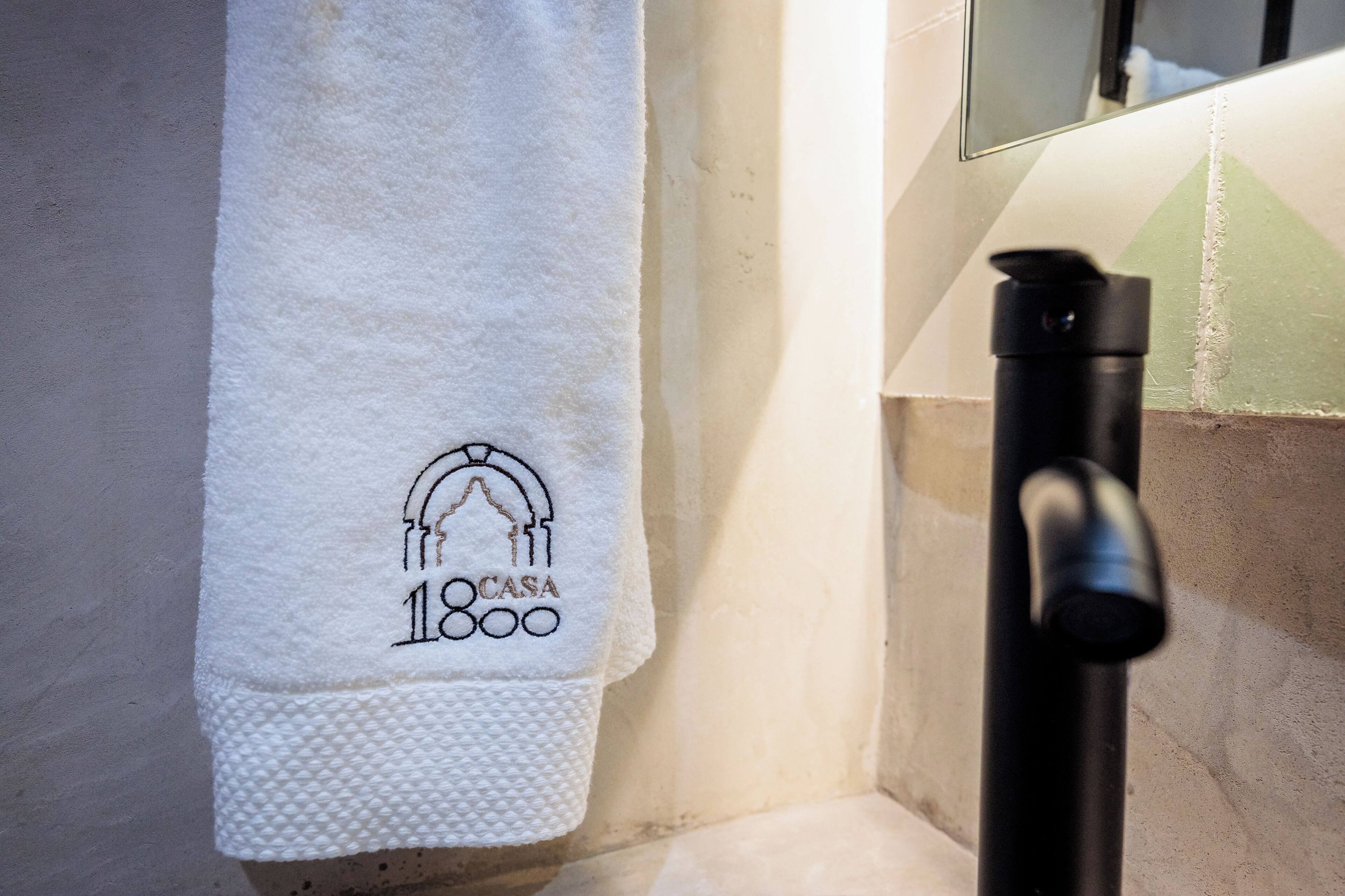 Une serviette blanche ornée d’un logo et de l’inscription « 18 CASA », accrochée à un mur.