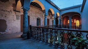 Une cour intérieure agrémentée d’arcades, de colonnes et d’un escalier.