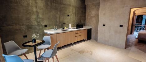 A modern kitchen with a central island, two chairs, and a small table with a potted plant.