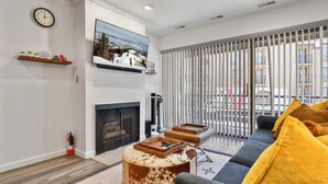 A modern living room with a fireplace, a mounted TV, and a sofa with yellow cushions. - New Claim by Park City Vacations (Park City)