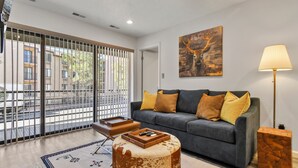 A modern living room with a grey sofa, a wooden coffee table, and a painting of a deer on the wall. - New Claim by Park City Vacations (Park City)