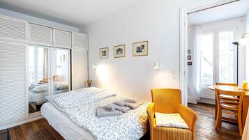 A bedroom with a bed, a chair, a table, and a wardrobe.