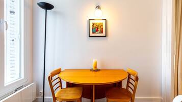 A round wooden table with four chairs, a lit floor lamp, and a framed picture on the wall.