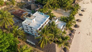 An aerial view of a beachfront hotel with multiple buildings, including a prominent multi-story structure with balconies and a smaller adjacent building. - Sands inn Hotel (Pwani Mchangani)