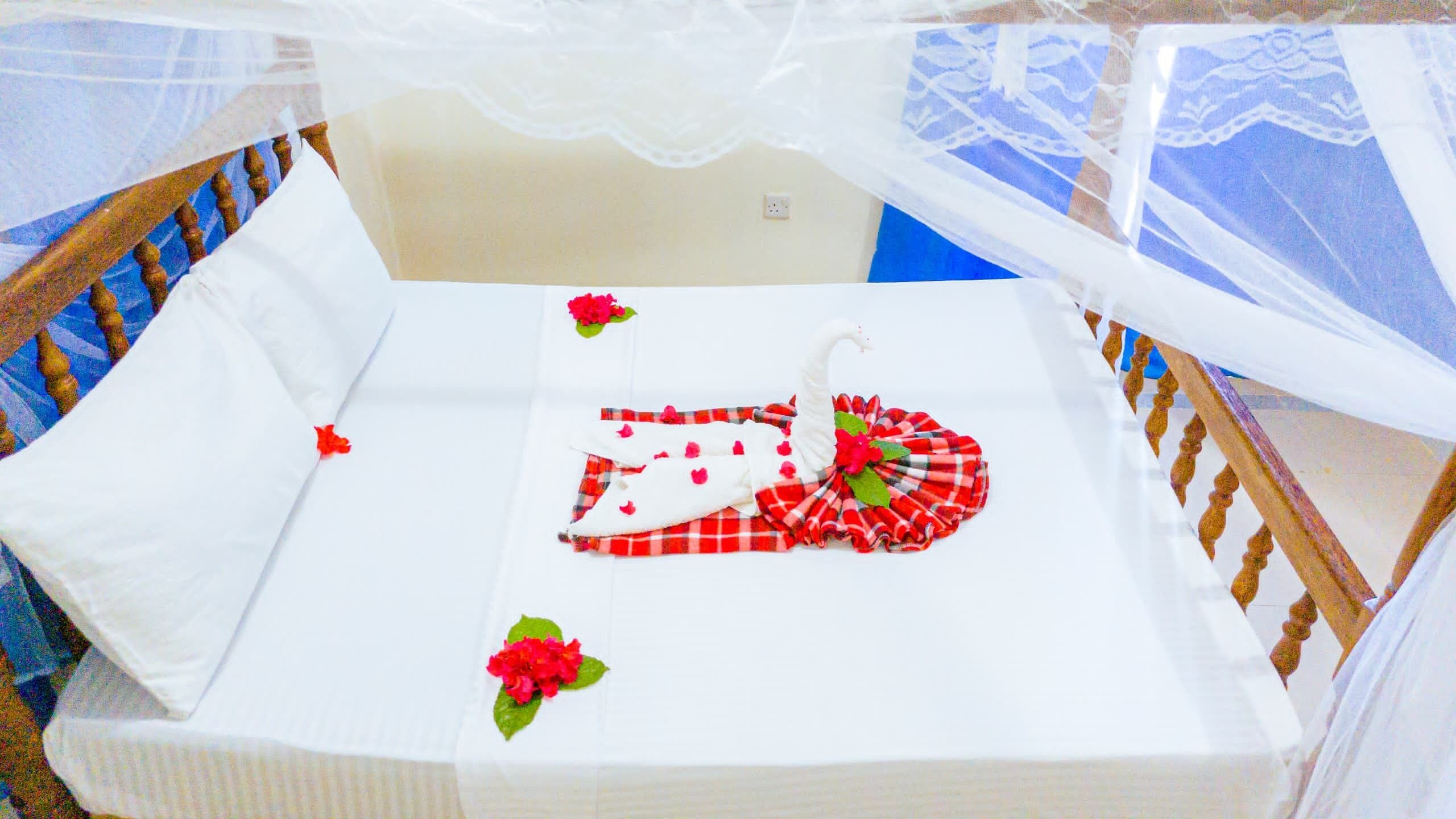 A crib with a white mattress, a red and white checkered blanket, and a white canopy.
