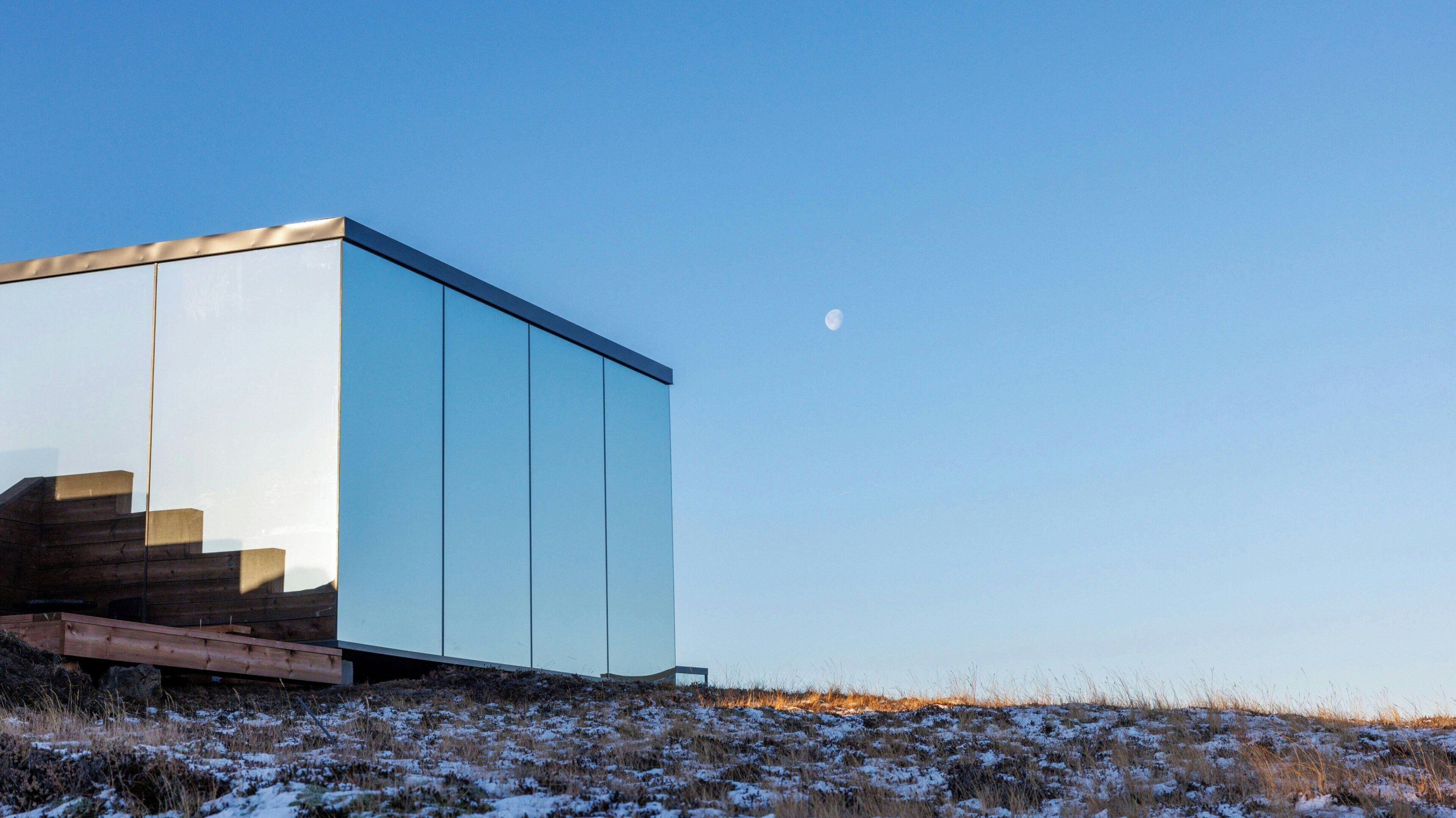 A modern building with a glass facade and wooden steps leading up to it.