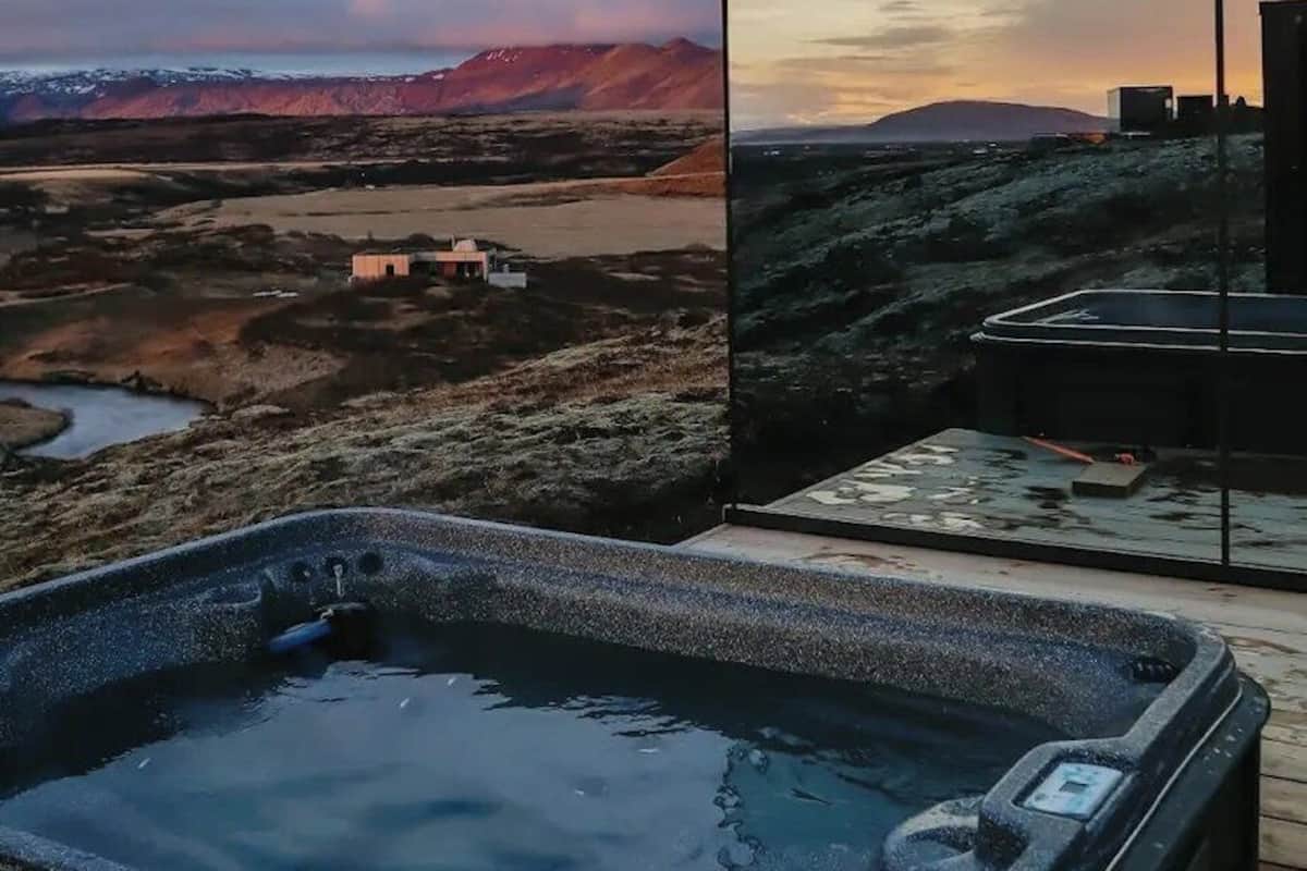 A hot tub with a view of a mountainous landscape and a sunset.