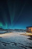 Paisaje nevado con un edificio de cristal y una montaña al fondo.